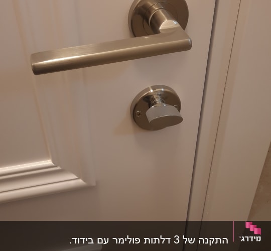 ידית דלת מתכתית על דלת לבנה